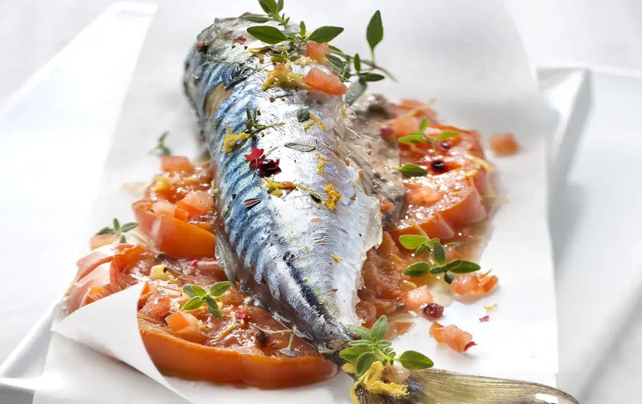 Maquereau entier, cuit en papillote avec des tomates et des herbes fraîches, prêt pour un barbecue savoureux.