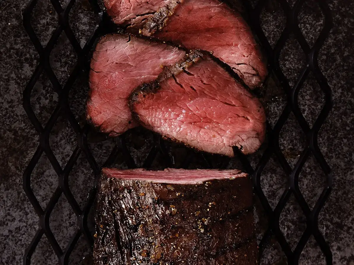 Tranches de filet mignon au barbecue, juteuses et rosées, sur une grille. Un délice pour les amateurs de viande grillée.